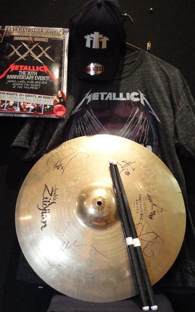 Amazing Metallica package – Zildian cymbal signed by the band members, drumsticks, assorted guitar picks, a program from the 30th Anniversary Shows at the Fillmore, a tee shirt and a hat.
